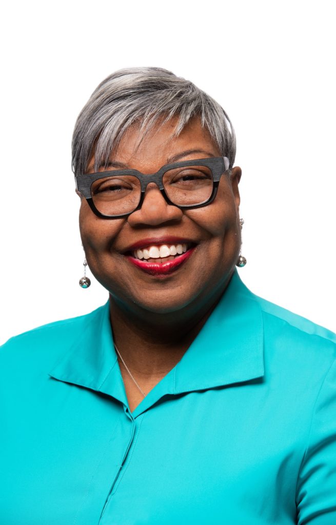 Close up of person smiling in aqua shirt wearing glasses
