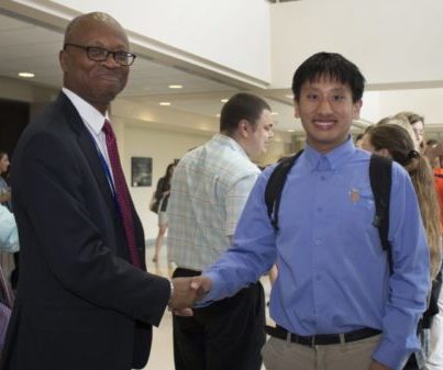 what appears to be a man in a suit shaking hands with a man blue project SEARCH shirt
